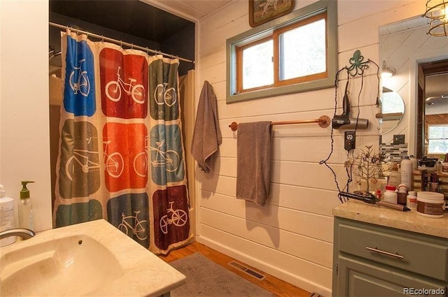 bathroom featuring vanity, hardwood / wood-style flooring, and wooden walls