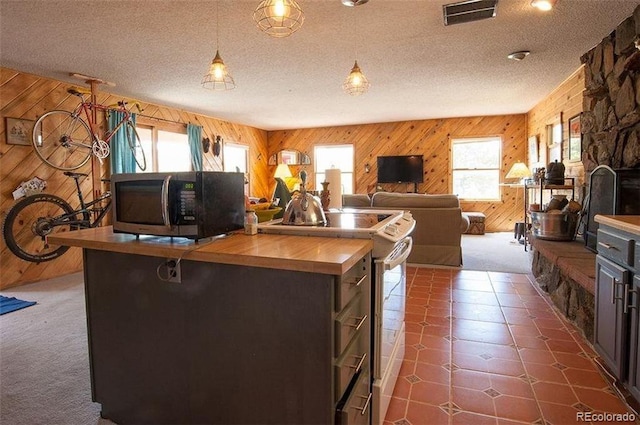 kitchen with wood walls, white range with electric stovetop, dark brown cabinetry, and a textured ceiling