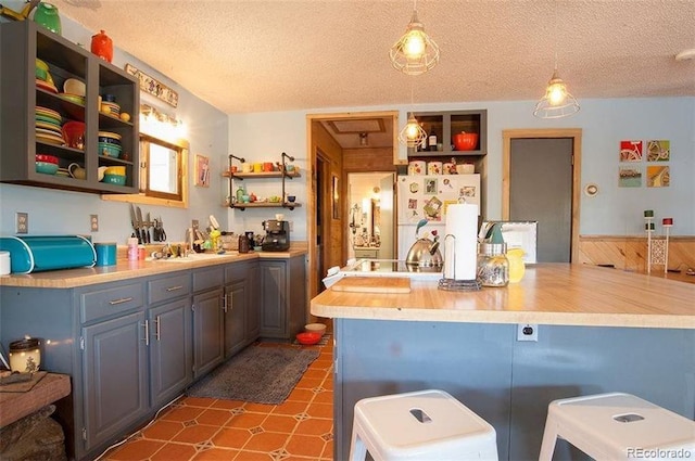 kitchen with pendant lighting, a textured ceiling, wood walls, and white refrigerator