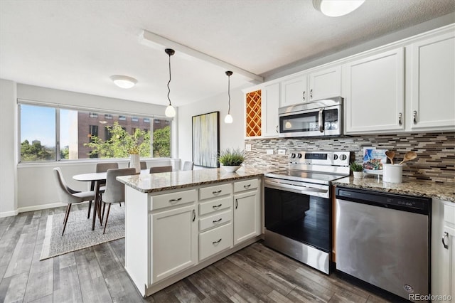 kitchen featuring white cabinets, stainless steel appliances, and hanging light fixtures