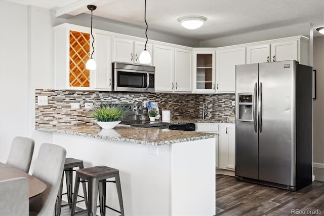 kitchen with kitchen peninsula, tasteful backsplash, decorative light fixtures, white cabinetry, and stainless steel appliances