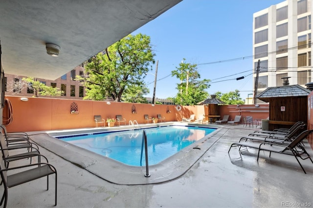 community pool with a patio and fence