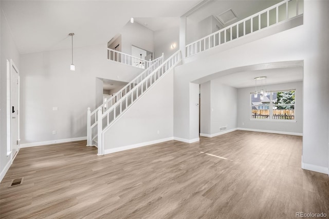 9147 W Rockland Pl, Littleton, CO 80128 - unfurnished living room with a towering ceiling, wood finished floors, arched walkways, and a chandelier