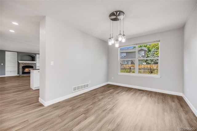 9147 W Rockland Pl, Littleton, CO 80128 - unfurnished dining area with wood finished floors, a warm lit fireplace, built in shelves, and recessed lighting
