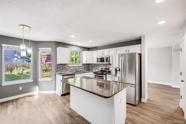 9147 W Rockland Pl, Littleton, CO 80128 - kitchen featuring stainless steel appliances, dark stone counters, backsplash, light wood finished floors, and white cabinets