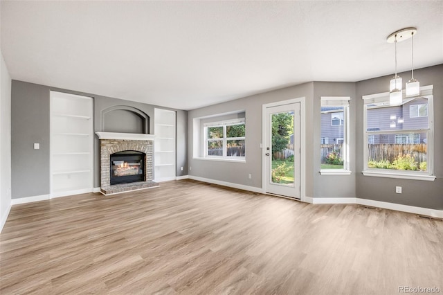 9147 W Rockland Pl, Littleton, CO 80128 - unfurnished living room with light wood-style flooring, a fireplace, and built in shelves