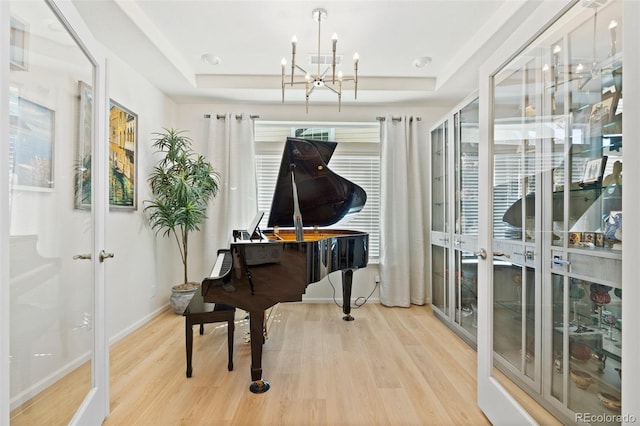 sitting room featuring a raised ceiling, wood finished floors, french doors, and a chandelier