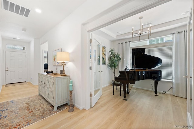 living area featuring visible vents, baseboards, light wood-type flooring, and an inviting chandelier