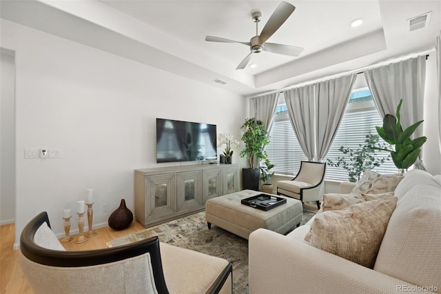 living room featuring wood finished floors, visible vents, a tray ceiling, recessed lighting, and ceiling fan