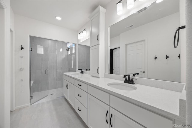 bathroom featuring double vanity, visible vents, a shower stall, and a sink