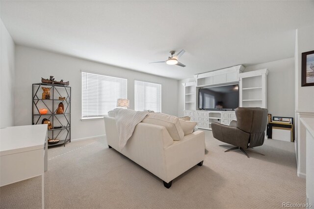 living area featuring light colored carpet, baseboards, and ceiling fan