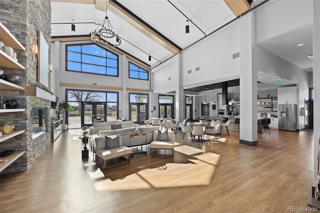 living area featuring a stone fireplace, lofted ceiling with beams, and wood finished floors