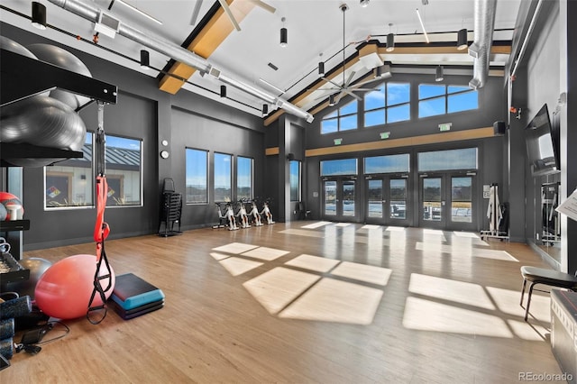 exercise area with high vaulted ceiling, wood finished floors, and a ceiling fan