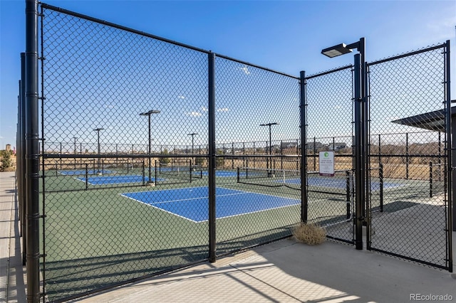 view of tennis court featuring a gate and fence