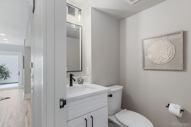 bathroom featuring toilet, wood-type flooring, and vanity