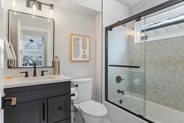 full bathroom with enclosed tub / shower combo, vanity, and toilet