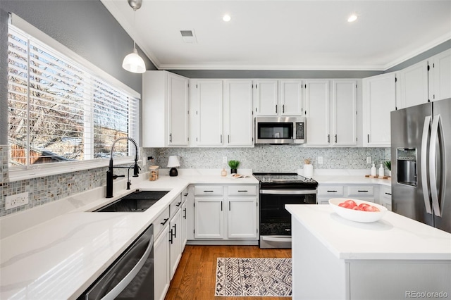 kitchen with stainless steel appliances, a sink, white cabinetry, backsplash, and pendant lighting