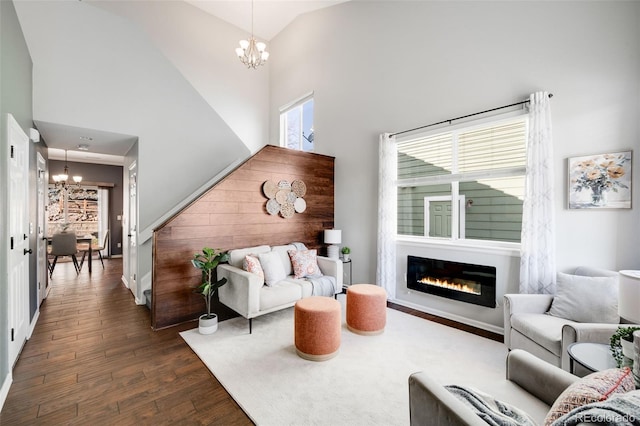 living room with high vaulted ceiling, dark wood finished floors, a notable chandelier, and a glass covered fireplace