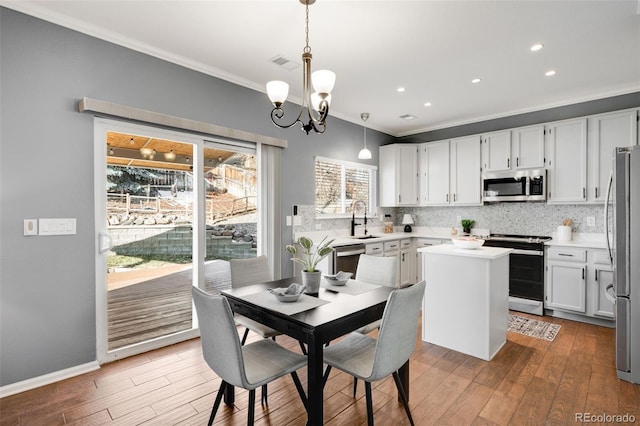 kitchen with white cabinetry, light countertops, appliances with stainless steel finishes, hanging light fixtures, and a center island