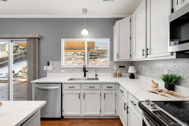 kitchen with decorative backsplash, appliances with stainless steel finishes, hanging light fixtures, white cabinetry, and a sink