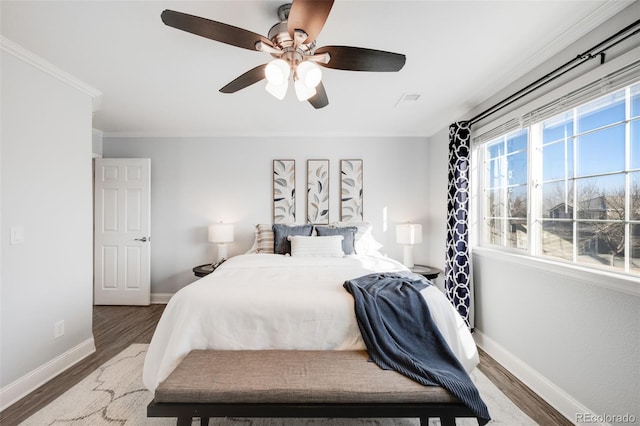 bedroom featuring ceiling fan, crown molding, baseboards, and wood finished floors