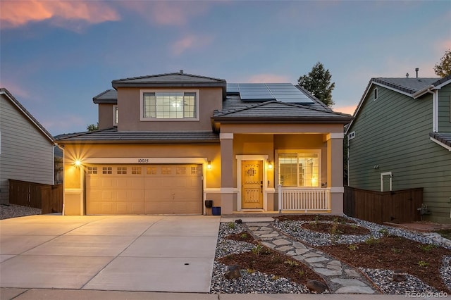 view of front of property with covered porch, driveway, stucco siding, and roof mounted solar panels