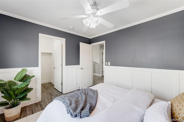 bedroom with ceiling fan, crown molding, a spacious closet, and wood finished floors