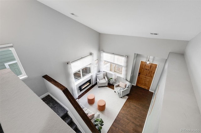 living area featuring lofted ceiling, baseboards, visible vents, and dark wood-type flooring