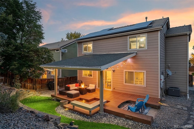 back of property with an outdoor living space, fence, a deck, and roof mounted solar panels