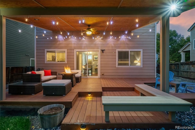 wooden deck with an outdoor living space with a fire pit, fence, and ceiling fan