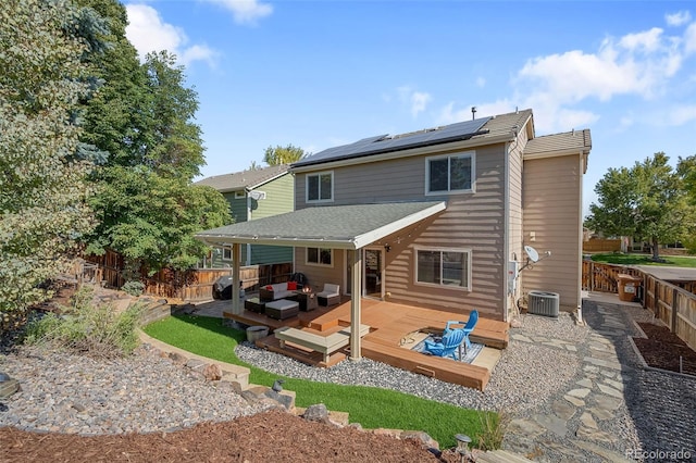 rear view of house with outdoor lounge area, a fenced backyard, a wooden deck, and solar panels