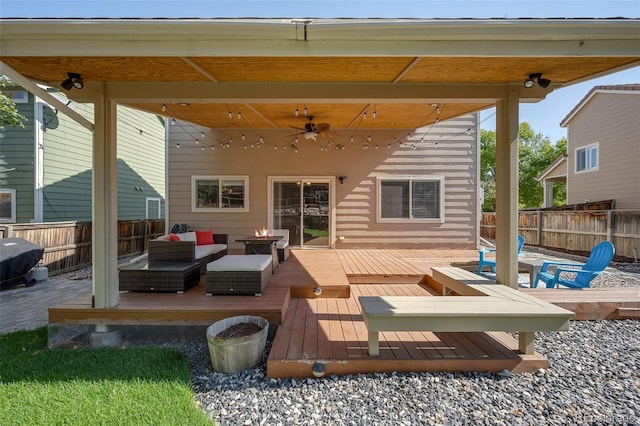 wooden terrace with ceiling fan, fence, and an outdoor living space