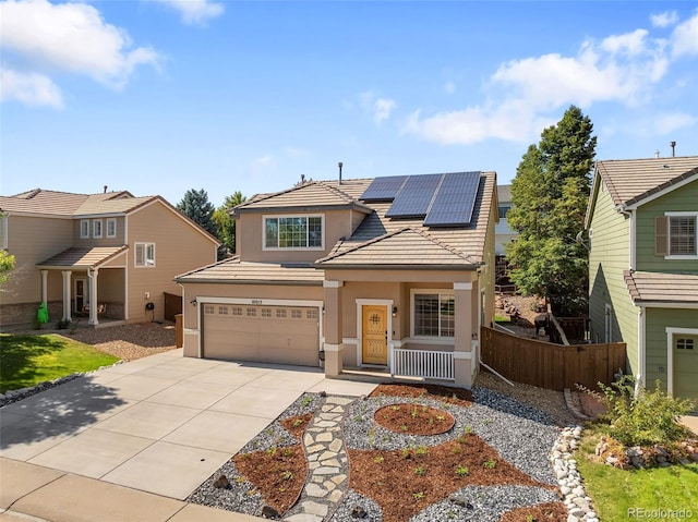 traditional-style house featuring stucco siding, solar panels, fence, a garage, and driveway