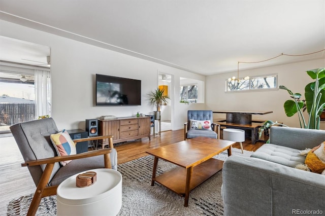 living room featuring baseboards, wood finished floors, and ceiling fan with notable chandelier