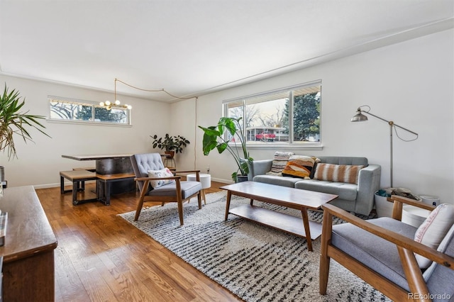 living room featuring a notable chandelier, baseboards, and hardwood / wood-style flooring