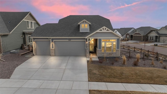 view of front facade featuring fence, an attached garage, a shingled roof, concrete driveway, and stone siding