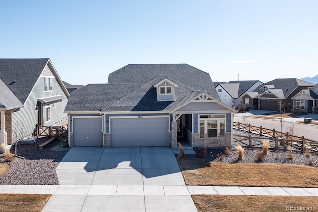 view of front of property with stone siding, fence, concrete driveway, a shingled roof, and a garage