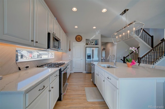 kitchen with a sink, premium appliances, recessed lighting, white cabinets, and light wood finished floors