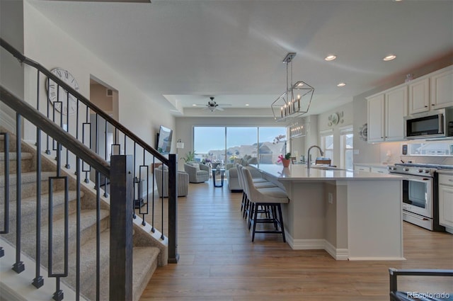 kitchen with light wood finished floors, white cabinets, appliances with stainless steel finishes, and light countertops