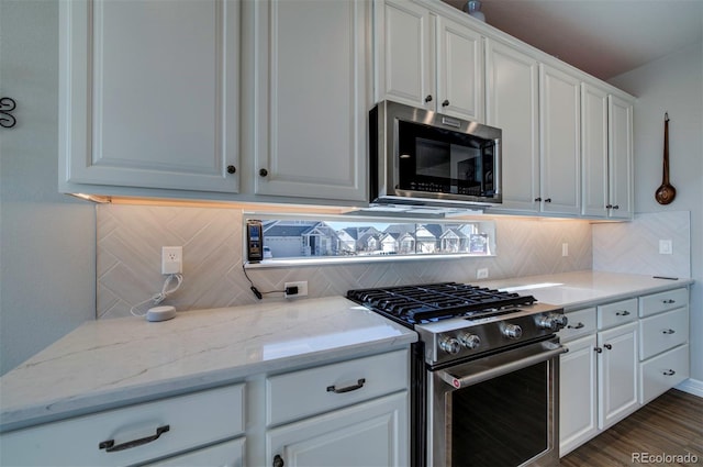 kitchen with dark wood-type flooring, light stone counters, decorative backsplash, white cabinets, and stainless steel appliances