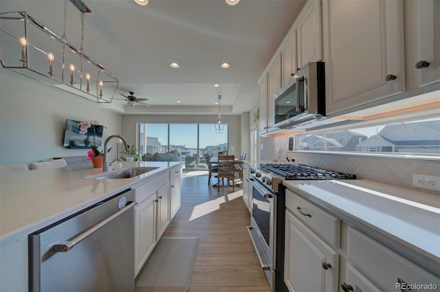 kitchen featuring a sink, stainless steel appliances, open floor plan, and light countertops