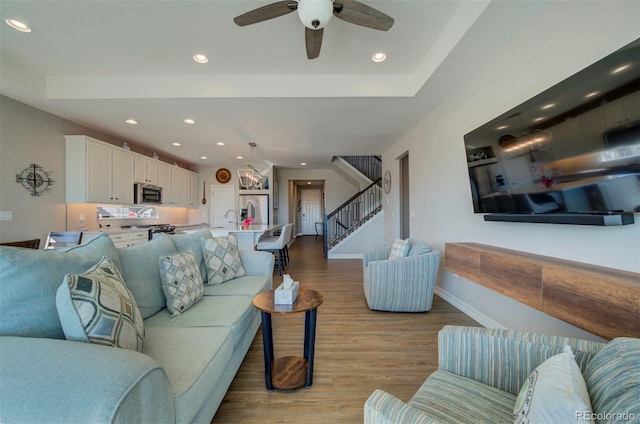 living area featuring ceiling fan, baseboards, stairway, recessed lighting, and wood finished floors