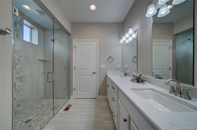 bathroom featuring a shower stall, double vanity, visible vents, and a sink