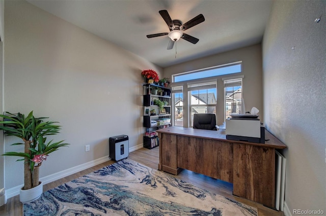 office area with a ceiling fan, baseboards, and light wood-type flooring