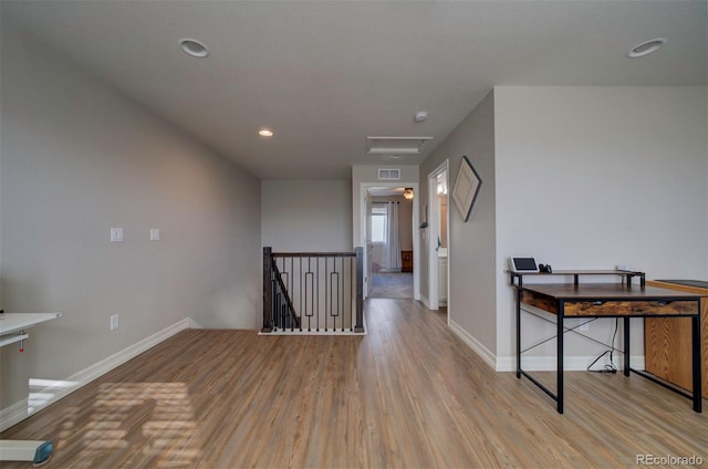 hall featuring baseboards, an upstairs landing, attic access, and wood finished floors