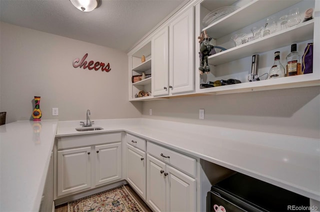 kitchen with open shelves, white cabinets, light countertops, and a sink