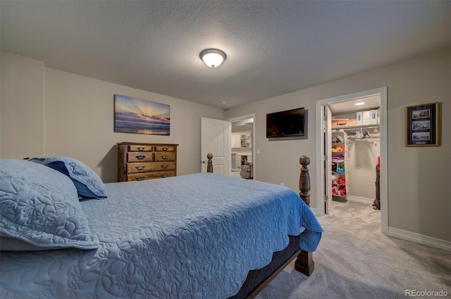 carpeted bedroom featuring a walk in closet, baseboards, a closet, and a textured ceiling