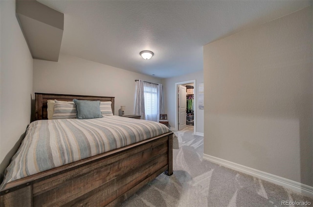 bedroom featuring a walk in closet, carpet flooring, and baseboards