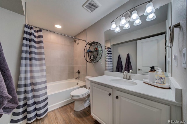 bathroom featuring vanity, wood finished floors, visible vents, shower / bath combo with shower curtain, and toilet