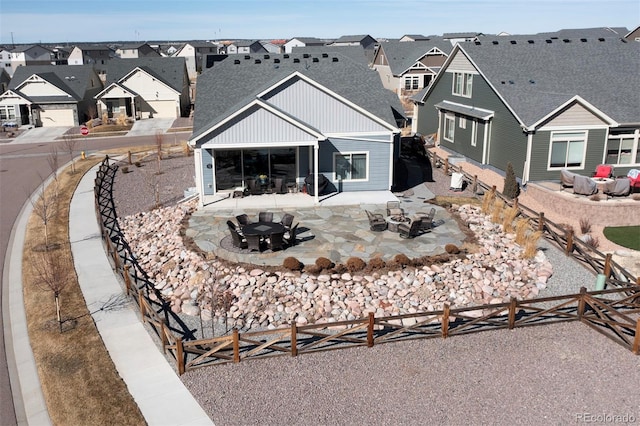 rear view of house featuring a residential view, an outdoor fire pit, a fenced backyard, and a patio area